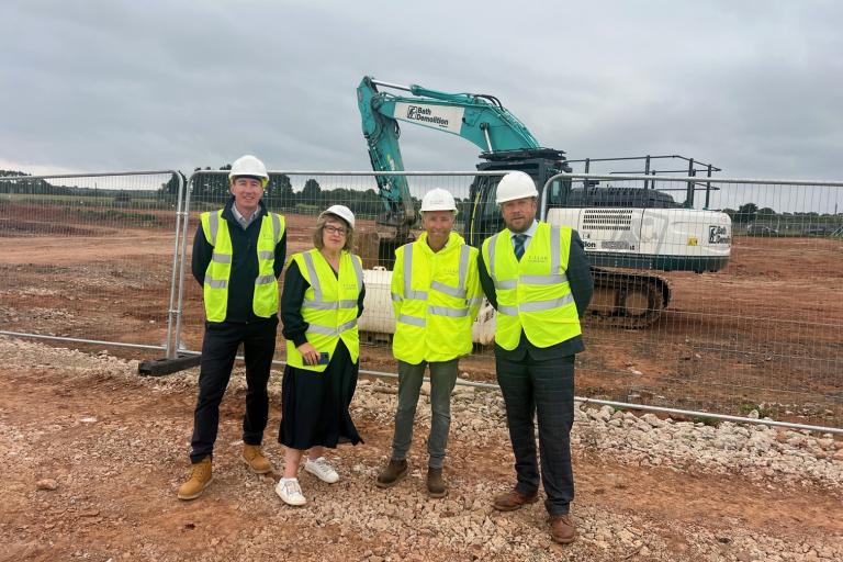 Four people in high vis vests standing in front of construction site