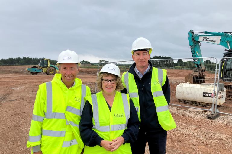 3 people standing in front of building site wearing high vis vests