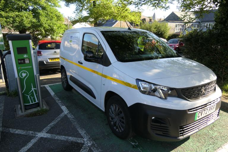 Electric small council van parked in car park next to an EV charger