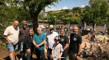 A picture of stakeholders and funders for the Kingsbridge skatepark, including South Hams councillors, members of the Kingsbridge Skatepark Group and Kingsbridge Town Council. They are stood in a group with the skatepark in the background.