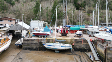 a boat being lifted out of the water surrounded by multiple boats on jetty