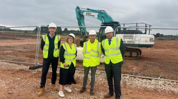 Four people in high vis vests standing in front of construction site