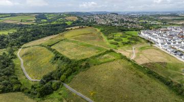 Green fields with path around the outside surrounded by fields. Housing estate to the north and east of the fields.