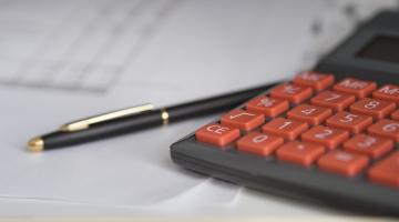 Calculator and pen lain on a piece of paper.